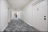 Modern apartment hallway with sleek white brick walls and plush gray carpeting leading to staircase.