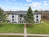 Charming apartment building with a modern exterior, surrounded by lush greenery and a welcoming path, ideal for cozy suburban living.