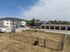 Charming apartment complex with ample parking, private fenced area, and scenic surroundings on a sunny day.