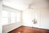 Bright room with elegant hardwood floors and large windows, featuring a sleek ceiling fan and a stylish door with mirror.