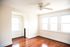 Bright room with polished hardwood floors, large windows, and a ceiling fan, offering a cozy and inviting atmosphere.