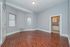 Bright and spacious living area with rich wooden floors and classic white trims, seamlessly connecting to a cozy kitchen.