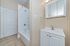 Modern bathroom featuring sleek white cabinetry, elegant sink, and pristine bathtub with shower.