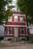 Charming red brick apartment building with large windows and a welcoming entrance, nestled among lush trees.
