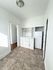 Bright, compact kitchen with white cabinetry and modern flooring, adjacent to a well-lit entryway.