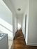 Charming hallway with natural light, featuring rich wooden floors and inviting white walls in a cozy apartment.