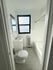 Bright and modern bathroom featuring elegant tile flooring, pristine white fixtures, and a large window for natural light.