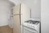 Cozy kitchen with a classic refrigerator and gas stove, complemented by spacious cabinetry and bright white walls.