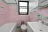 Charming vintage bathroom with pastel pink and green tiles, featuring a classic bathtub and a bright window view.
