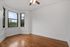 Bright, airy room with elegant hardwood floors and three large windows offering scenic views.