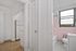 Charming apartment hallway highlighting vintage bathroom with pink tiles and natural light, adjacent to a cozy kitchen space with beige flooring.