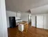 Charming kitchen area with wooden flooring, sleek black fridge, and cozy island with barstools for casual dining.