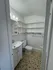 Charming tiled bathroom with modern white fixtures and ample shelving.