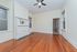 Charming living room with rich hardwood floors, elegant white fireplace, and classic ceiling fan, perfect for cozy gatherings.