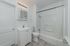 Bright and modern bathroom featuring a sleek vanity, accessible shower-bath combo, and elegant lighting.