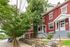 Charming brick apartment building with lush greenery and inviting front porches on a tree-lined street.