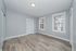 Bright and airy room with elegant laminate flooring, soft gray walls, and abundant natural light from double windows.
