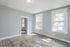 Bright and airy room with large windows, elegant wood flooring, and modern gray panel walls.