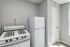 Charming kitchen corner featuring a classic white gas stove and an elegant refrigerator, set against soft gray paneling for a cozy feel.