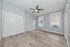 Bright and airy room with modern laminate flooring, featuring a sleek ceiling fan and large windows.