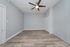 Sleek modern room with elegant wooden flooring, stylish ceiling fan, and soothing grey walls offering a spacious and versatile living area.