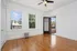 Bright and airy room with elegant hardwood floors, large windows offering scenic views, and a door leading to a charming outdoor patio.