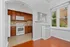 Charming kitchen with rich wood cabinets, modern appliances, and bright natural light through large windows.