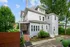 Charming multi-story home with a spacious veranda and lush greenery, perfect for serene living.