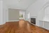 Charming living room with elegant hardwood floors, a cozy fireplace, and a stylish arched window.