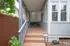 Charming front porch with elegant wooden steps and decorative lattice, offering a cozy entryway surrounded by lush greenery and vibrant flowers.