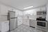 Modern kitchen with stainless steel appliances, elegant white cabinetry, and intricate patterned flooring.
