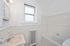 Charming bathroom featuring a sleek white design with a bathtub, radiant natural light, and vintage radiator heating.