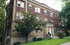 Charming brick apartment building with lush green surroundings, showcasing elegance and inviting architecture.