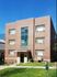 Elegant brick apartment building with large windows and a well-maintained lawn.