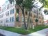 Elegant brick apartment building with green accents and lush landscaping.