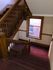 Elegant wooden staircase with classic railings and red carpet leading to a sunlit window.