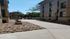 Inviting courtyard with stone pathway and modern brick buildings under a clear blue sky.