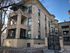 Elegant four-story brick apartment building with ornate wrought iron gate and balconies.