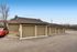 Multiple beige garages with a sleek red car parked nearby under a clear blue sky.