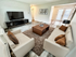 Stylish living room featuring modern white sofas, a sleek TV unit, and elegant decor with a cozy atmosphere.