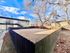 Inviting duplex with a large fenced yard, surrounded by mature trees and clear blue sky.