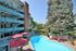 Inviting apartment complex with a pristine pool, red parasols, and lush greenery.