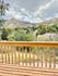Charming wooden balcony overlooking a beautiful mountain landscape under a partly cloudy sky.