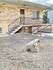Inviting apartment entrance with brick exterior, front steps, and a secure railing.