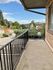 Charming balcony view overlooking lush greenery and distant hills, under a clear blue sky.