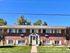 Brick apartment building with a well-maintained lawn, featuring a symmetrical design and multiple windows.