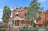 Elegant Victorian-style brick home with ornate porch and lush greenery.