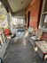 Cozy veranda with assorted seating, surrounded by classic brick and serene views.