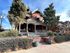Elegant Victorian-style brick home with a spacious porch, mature trees, and manicured landscaping.