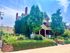 Elegant red brick house covered in lush greenery with a welcoming front porch and vibrant garden landscaping.